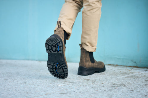 A persons feet in brown boots.