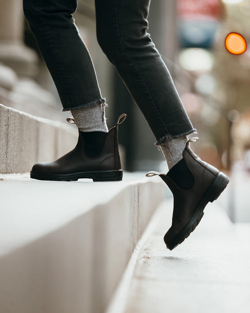 A person wearing black boots and jeans.