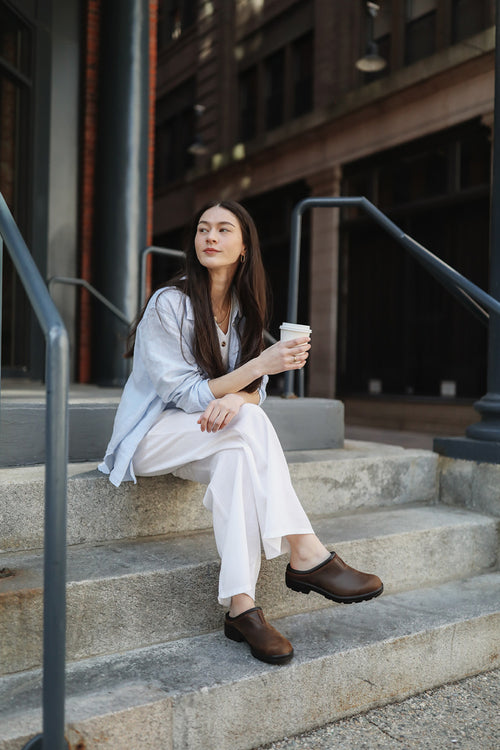 A woman sitting on steps holding a cup of coffee.